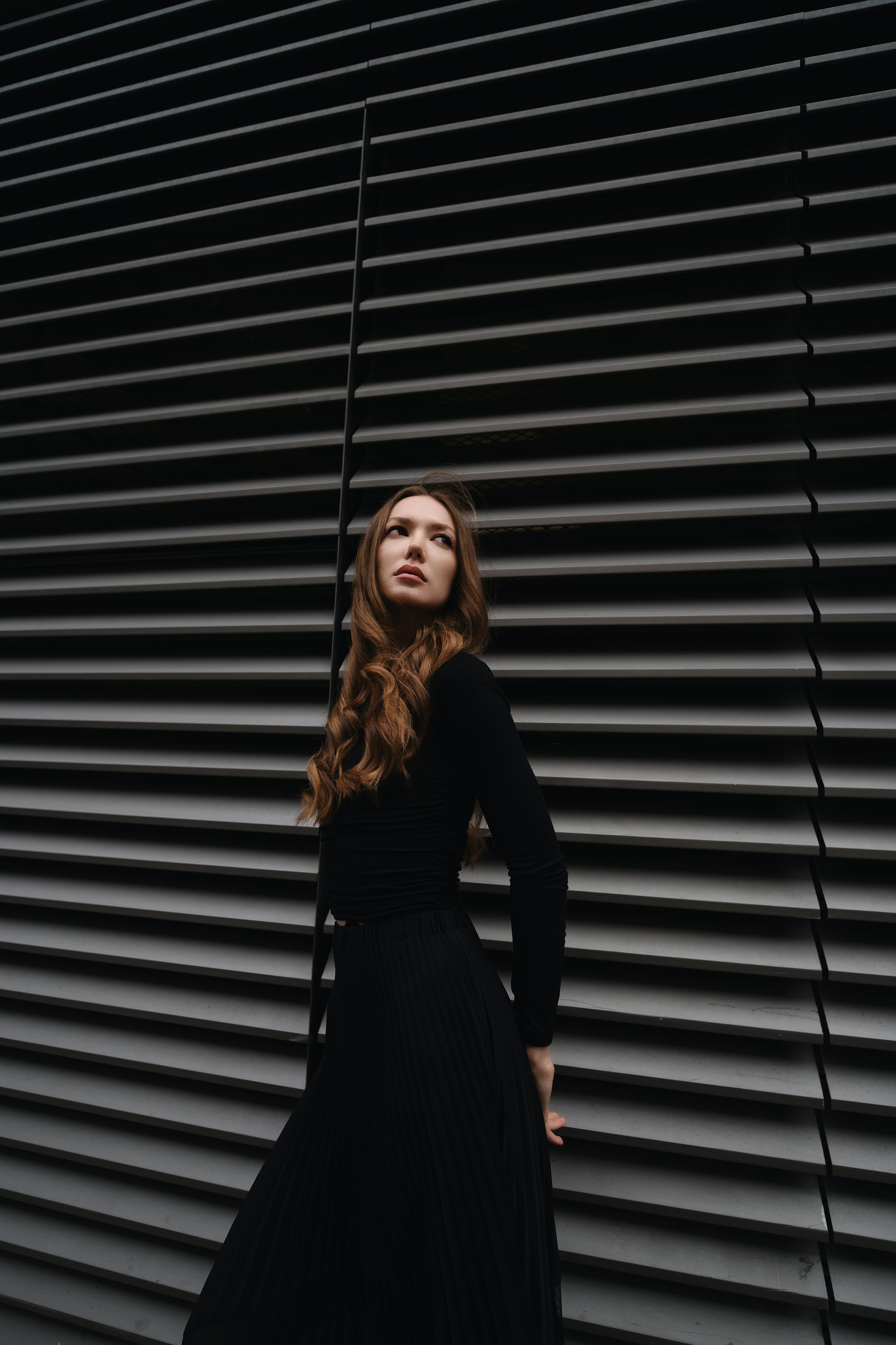 Stylish woman posing against modern architectural backdrop in London.
