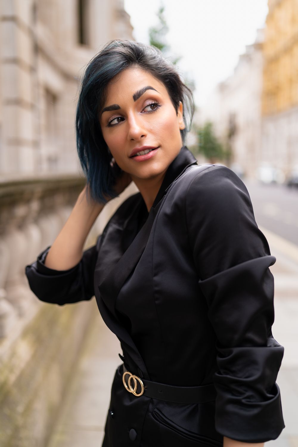 Stylish woman in a black jacket posing elegantly on a city street