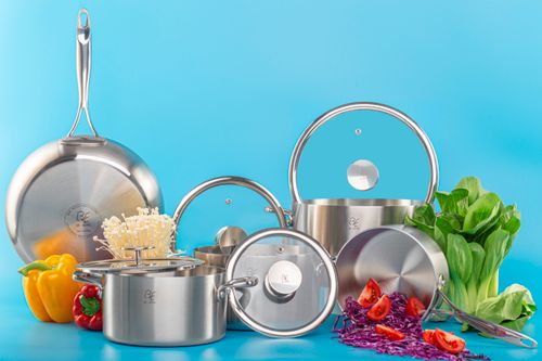 Free High-quality stainless steel pots and pans with fresh vegetables on a bright blue background. Stock Photo