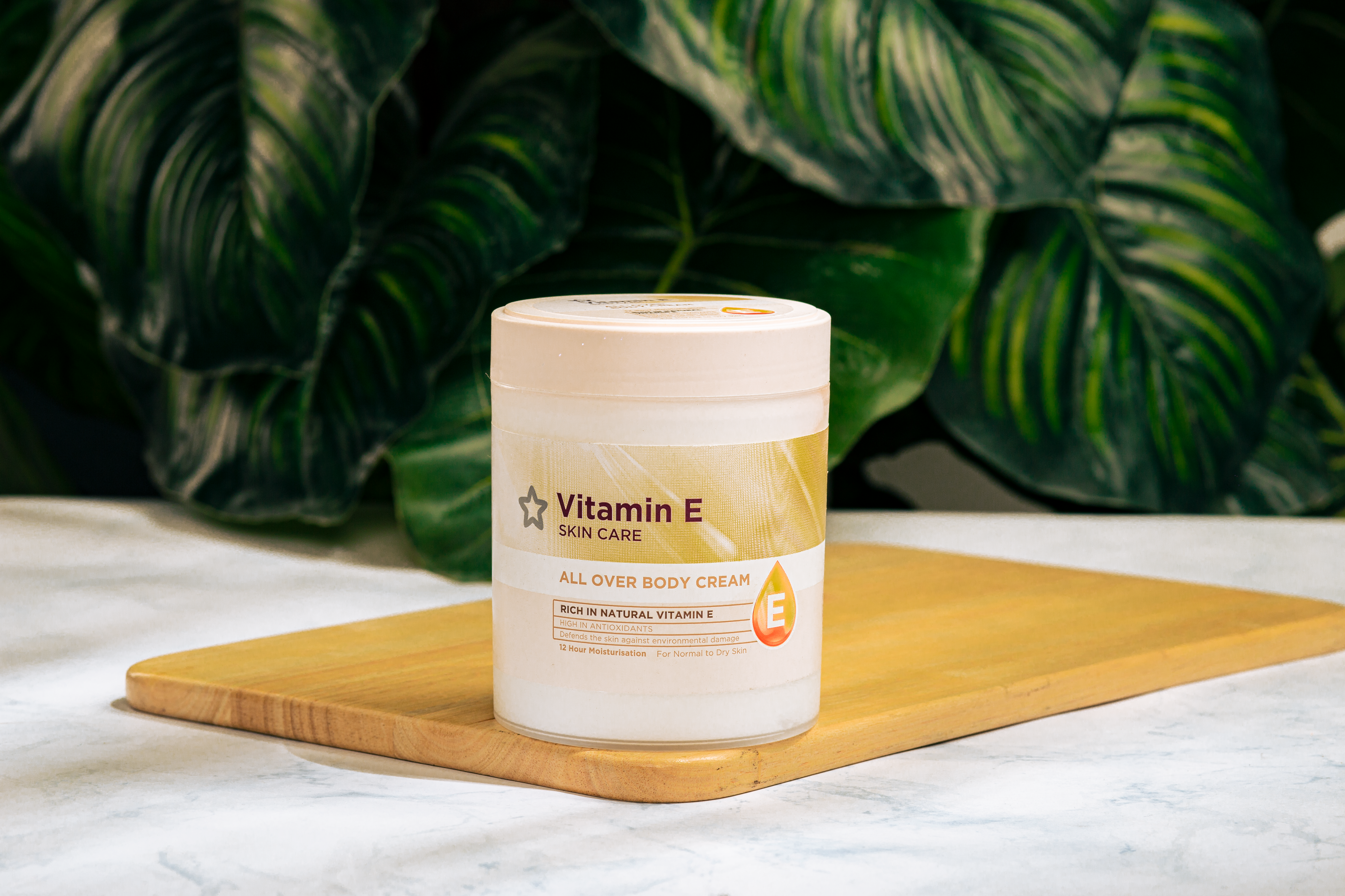 Vitamin E skin care cream on a wooden tray with green foliage background. - Evidence evidence guide for vitamin E skin aging meta-analysis