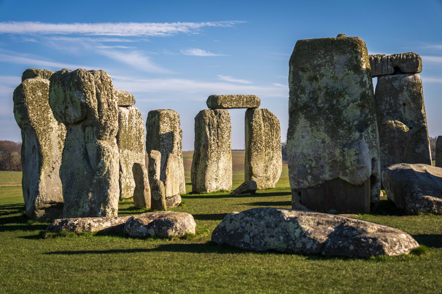 Iconic view of Stonehenge under a clear blue sky, showcasing ancient stone formations on a sunny day.