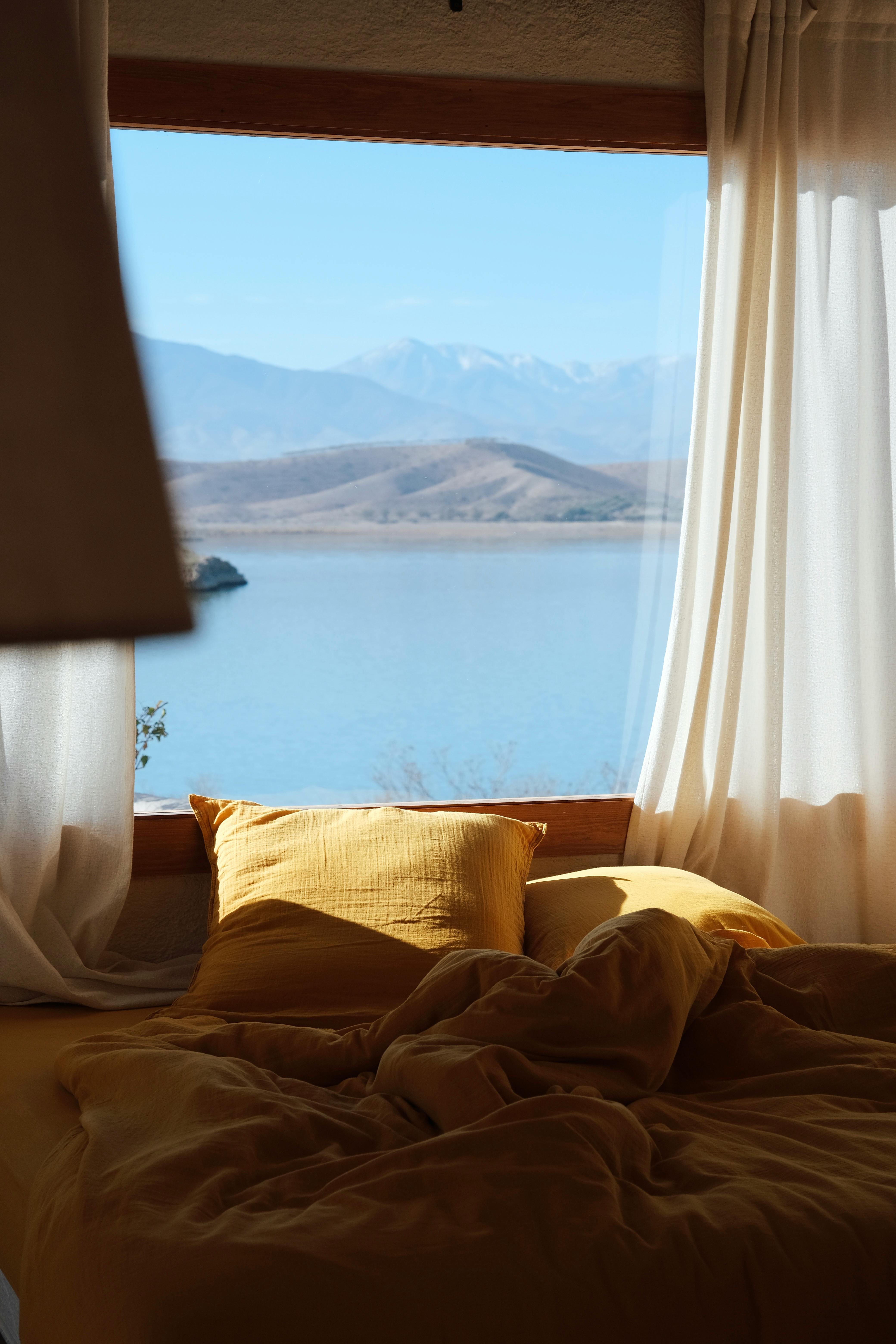 Serene bedroom with yellow bedding and Moroccan lake view. Ideal for travel inspiration.