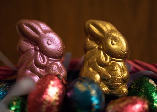 Free A vibrant Easter basket featuring foil-wrapped chocolate bunnies and eggs in rich colors. Stock Photo