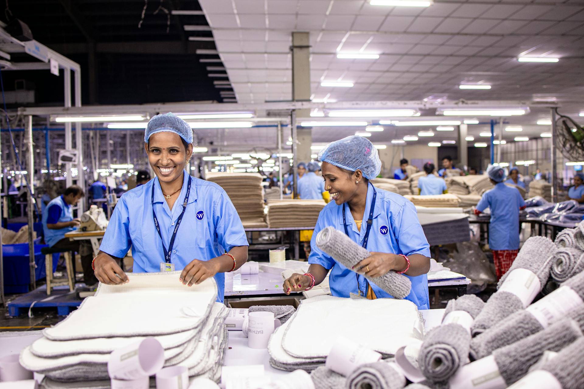 Two female workers in a textile factory sorting and packaging products, highlighting teamwork and industry.
