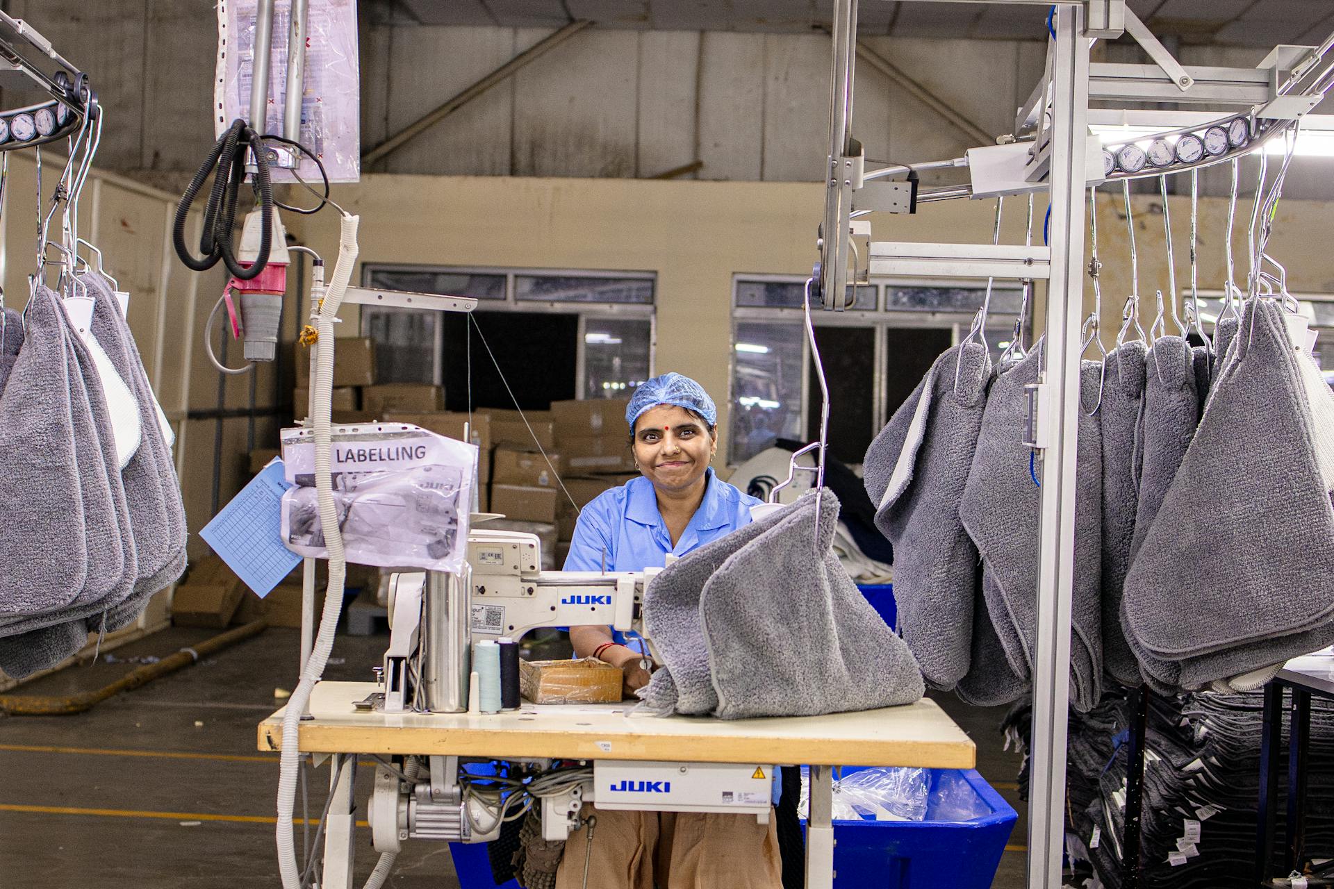 Textile worker sewing with Juki machine in a fabric labeling section of a factory.