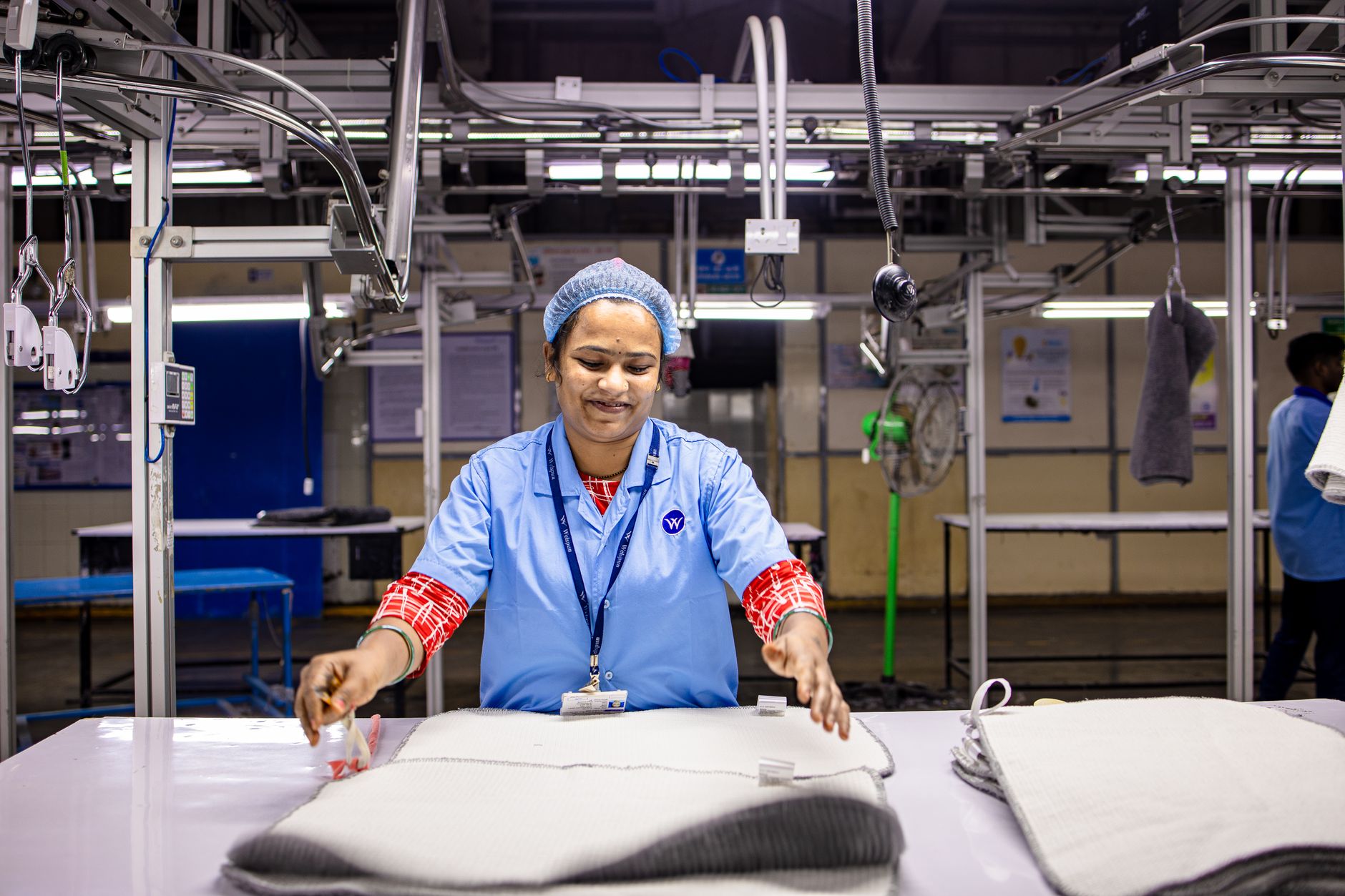 A dedicated textile worker processes garments on a factory assembly line.