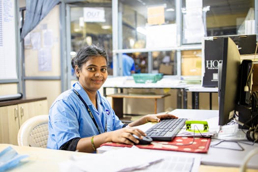 Young professional smiling at her desk in a modern office setting, engaging in computer work.