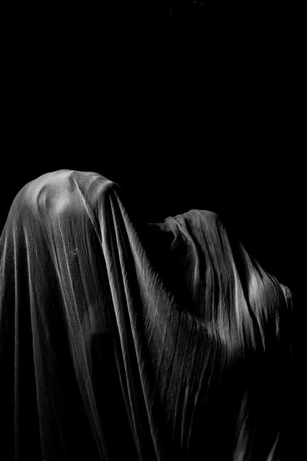 A captivating monochrome image of a draped figure against a dark background.