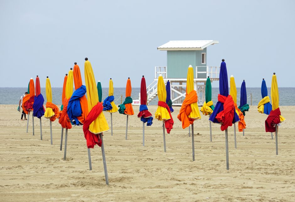 Vibrant beach umbrellas at Deauville beach in Normandie, France, with a tranquil seascape.