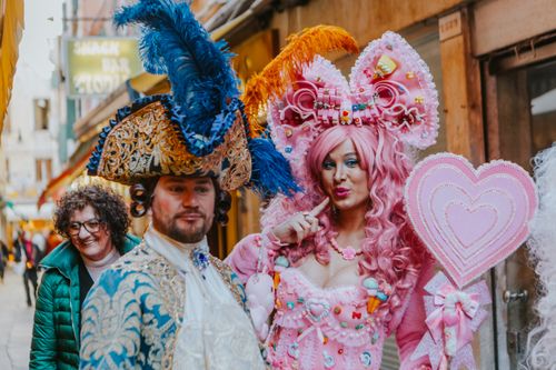 Free Vibrant costumed characters enjoying a lively street festival, showcasing intricate attire and playful expressions. Stock Photo