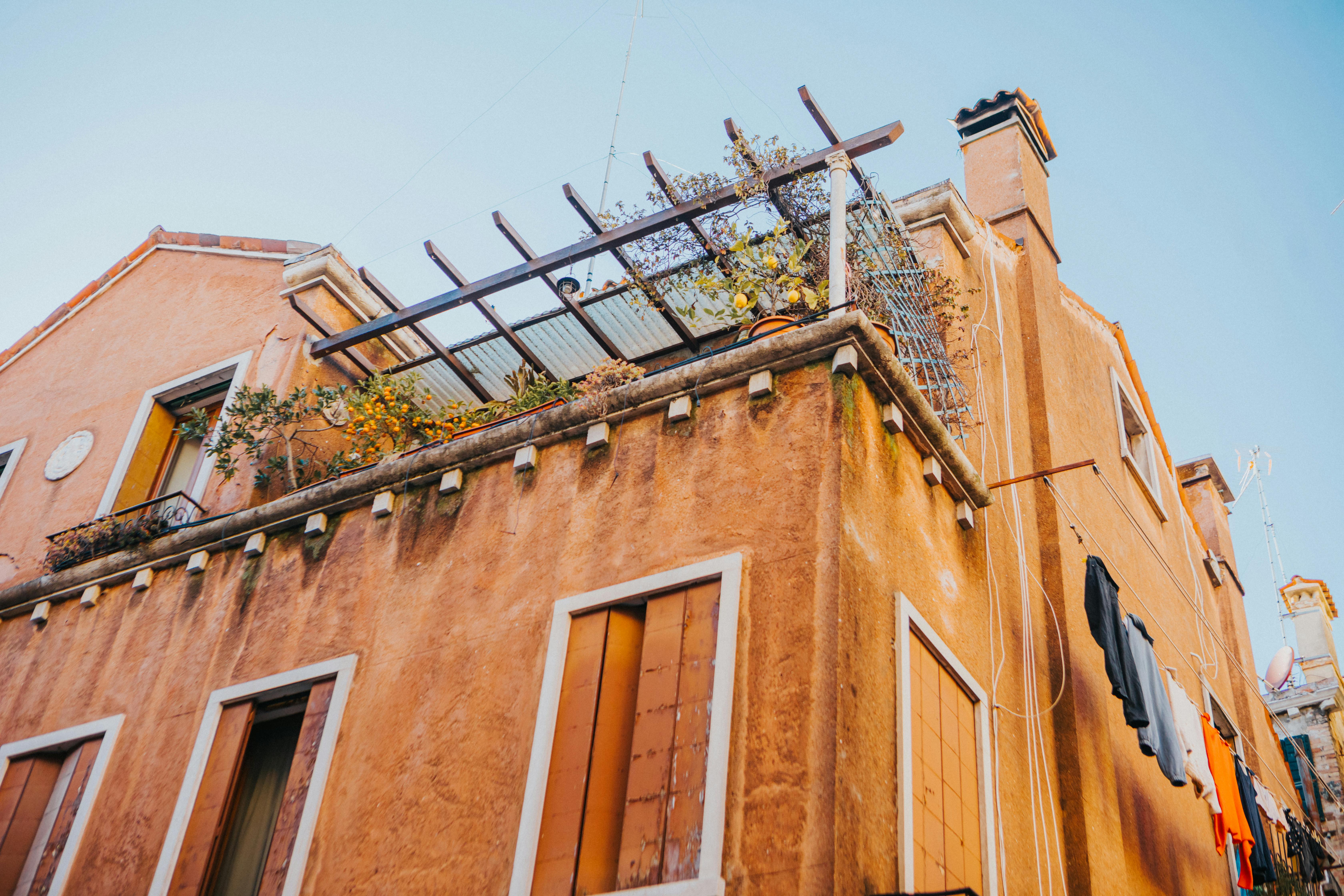 Explore a rustic Mediterranean building featuring a charming balcony with lush greenery and clothesline.