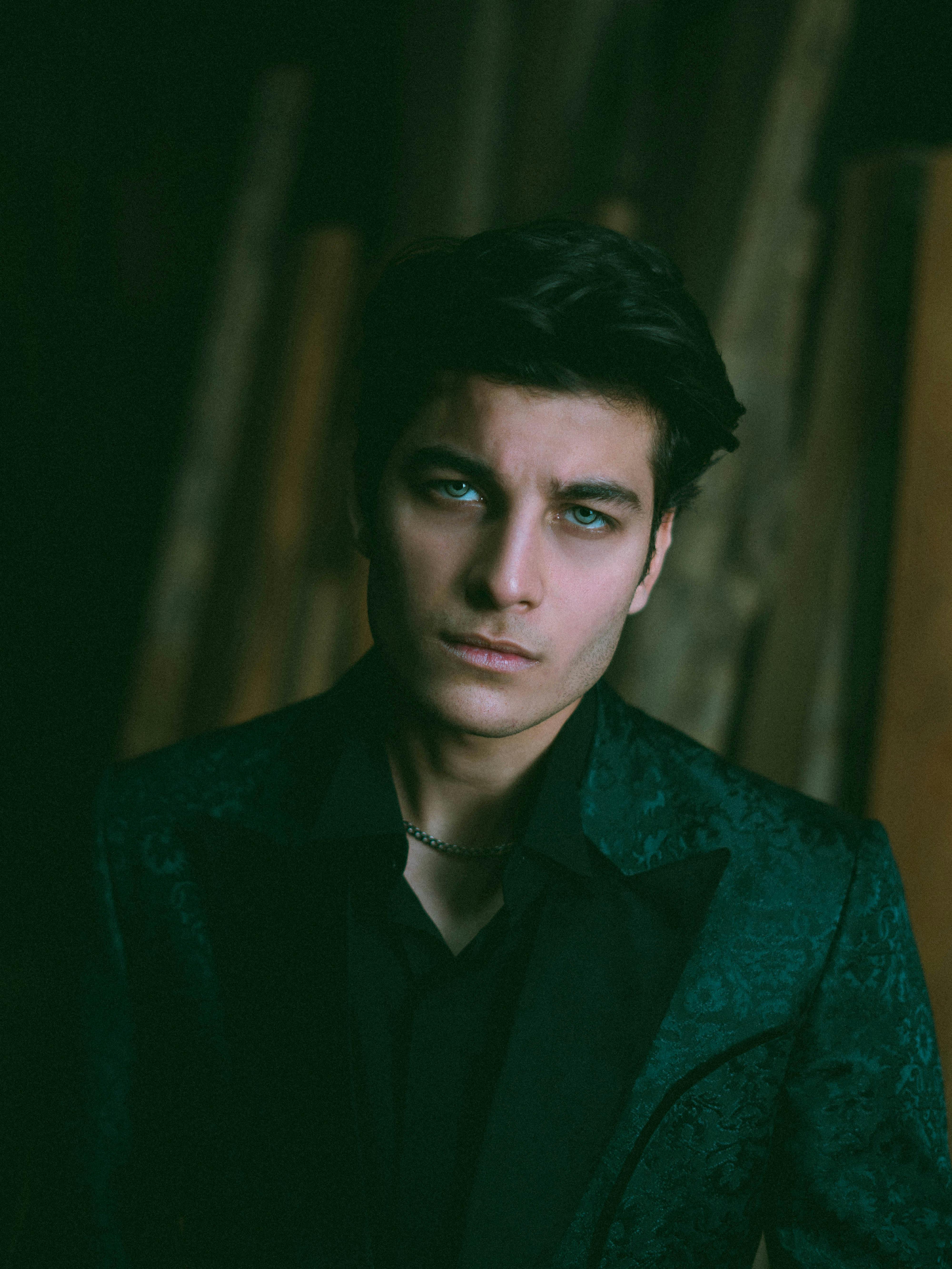 Young man in a dark green suit, capturing a moody and introspective feel.