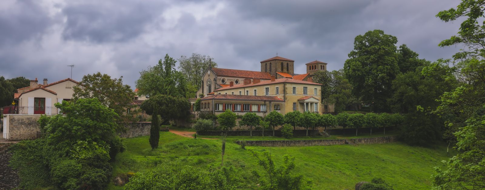 Scenic view of a historic church surrounded by lush greenery in Clisson, France.