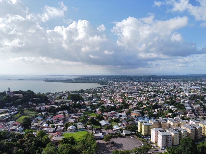 A stunning aerial view of a cityscape with lush greenery and blue waters under a vibrant sky.