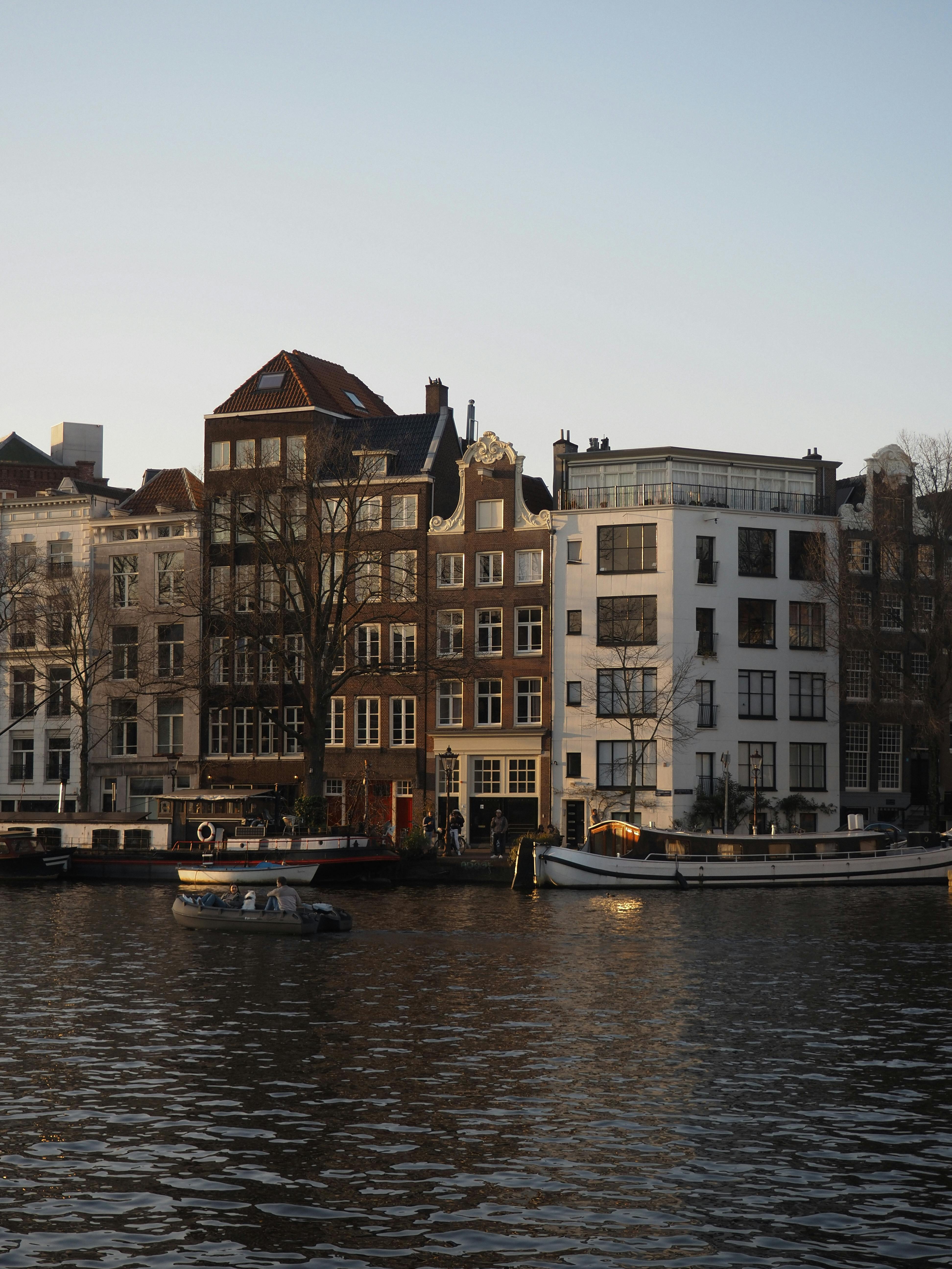 Charming canal view in Amsterdam with classic architecture and boats at sunset.