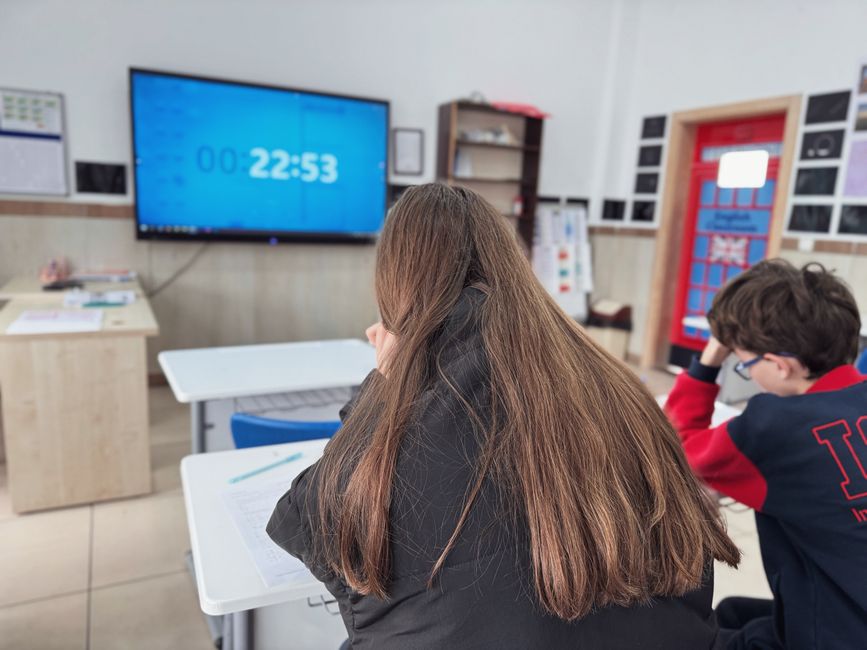 Students concentrating in a modern classroom with a digital timer on screen.