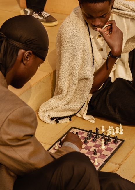 Two adults engaged in a deep chess game indoors in Ado Ekiti, Nigeria.