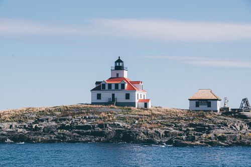 Free Charming lighthouse on a rocky seashore, ideal for travel or ocean-themed projects. Stock Photo