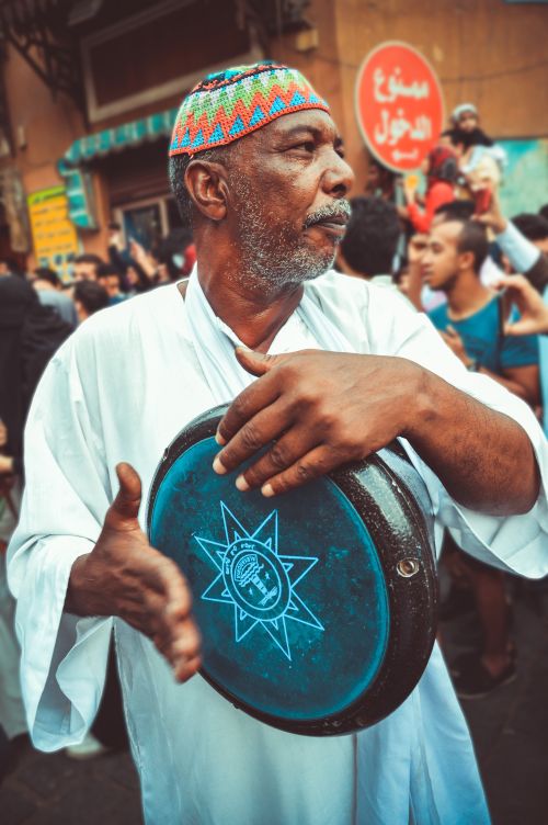 Free Elderly man playing darbuka during a vibrant street festival in Cairo, Egypt. Stock Photo