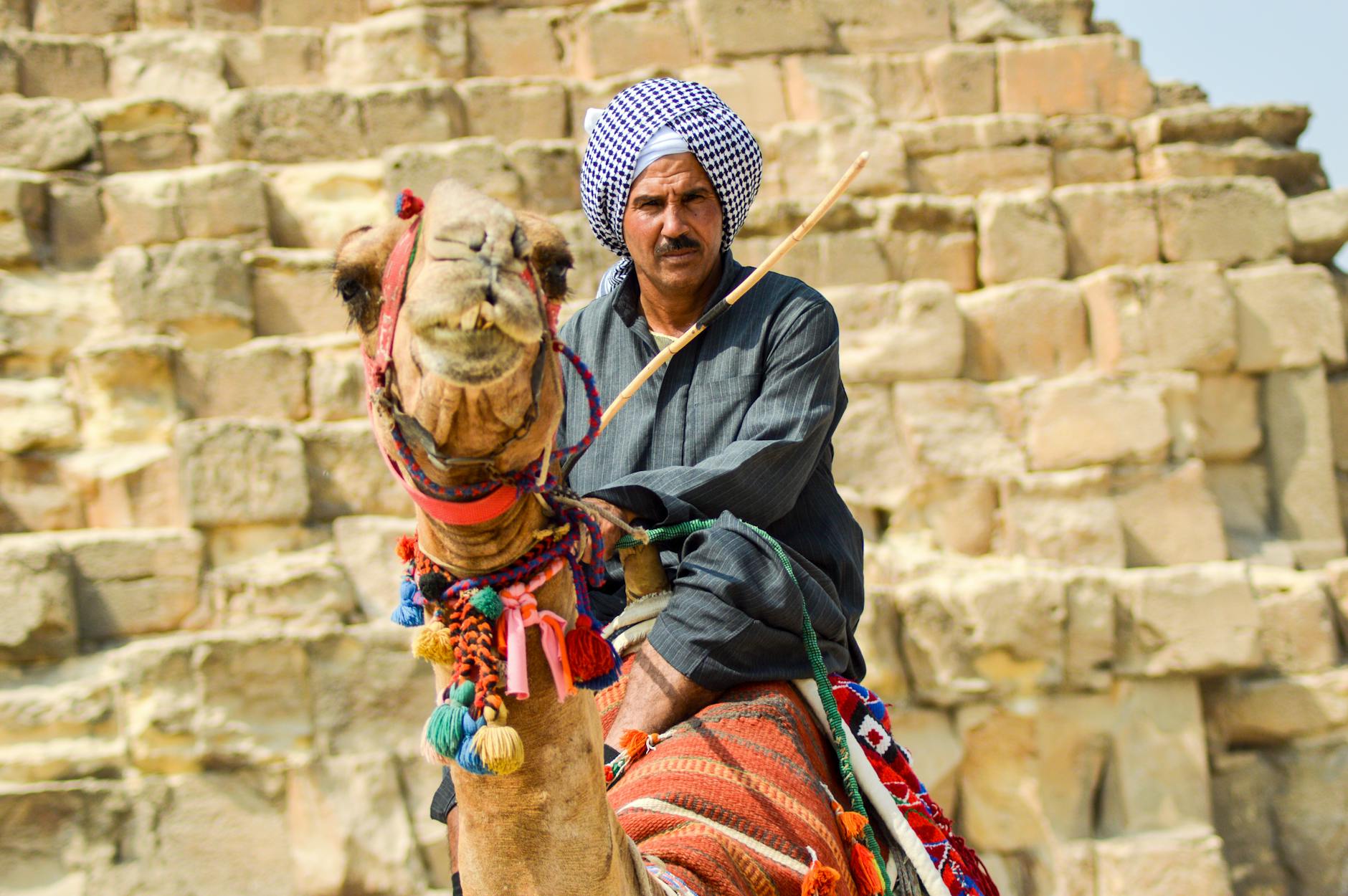 A Bedouin man rides a camel in front of the pyramids in Giza, Egypt.