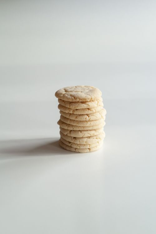 Stack of thick homemade sugar cookies with lightly golden edges on a white surface.
