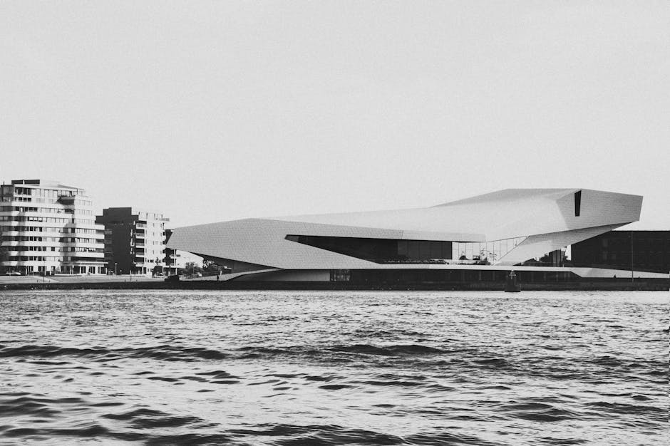Grayscale image of modern architecture by the Amsterdam waterfront, showcasing urban design.