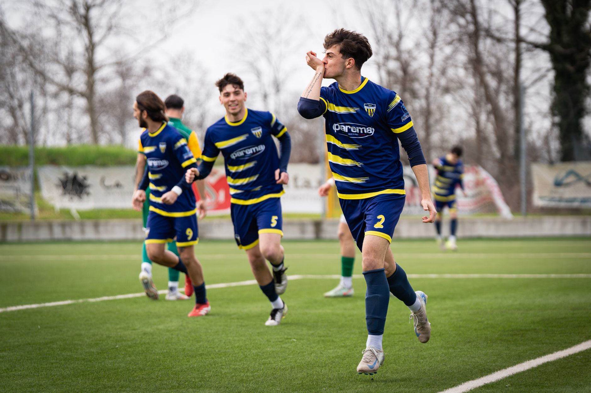 Young soccer players in blue uniforms celebrating a goal on a green field.