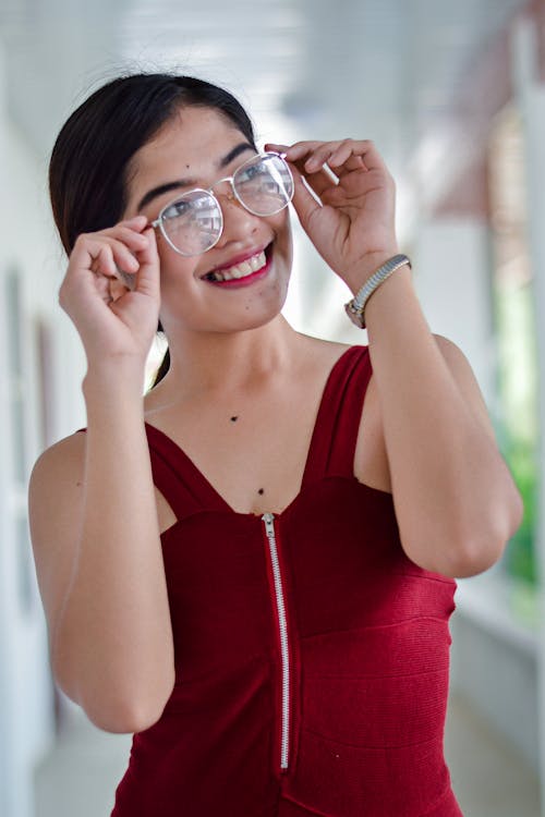 Free Woman Wearing Red Sleeveless Top While Holding Her Eyeglasses Stock Photo