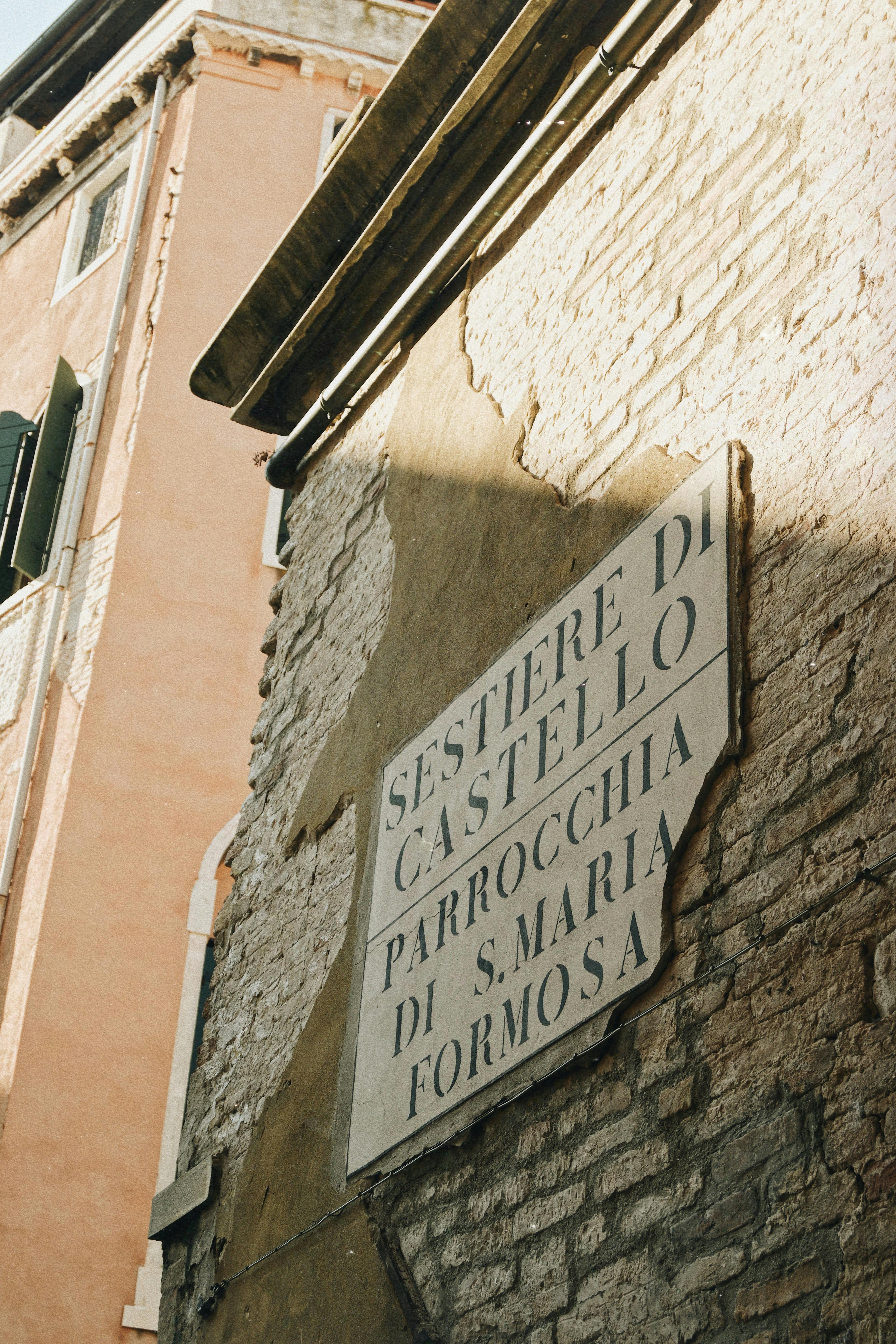Crumbling wall with sign to Parrocchia di S. Maria Formosa in Castello, Venice.