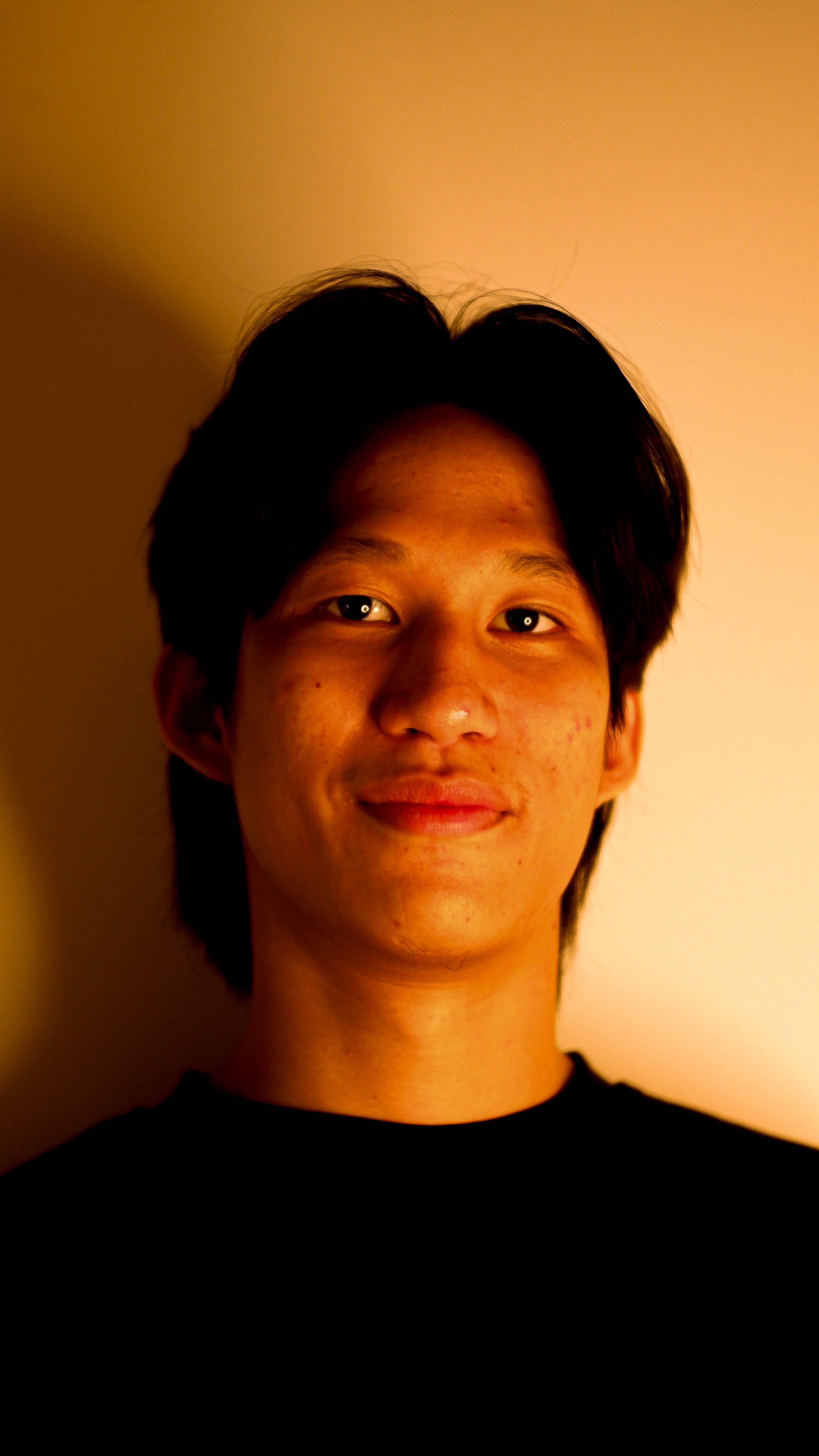 Portrait of a young adult with a gentle smile, captured in warm low light ambiance.