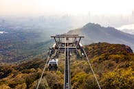 缆车滑过秋天的森林和山丘，远处是城市的天际线