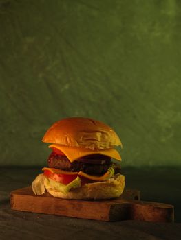 Appetizing cheeseburger with fresh ingredients on a rustic cutting board, ideal for food lovers.