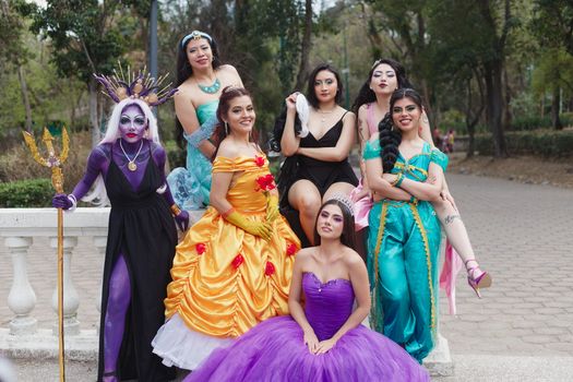 A vibrant group of women dressed as Disney princesses and villains in a park setting.