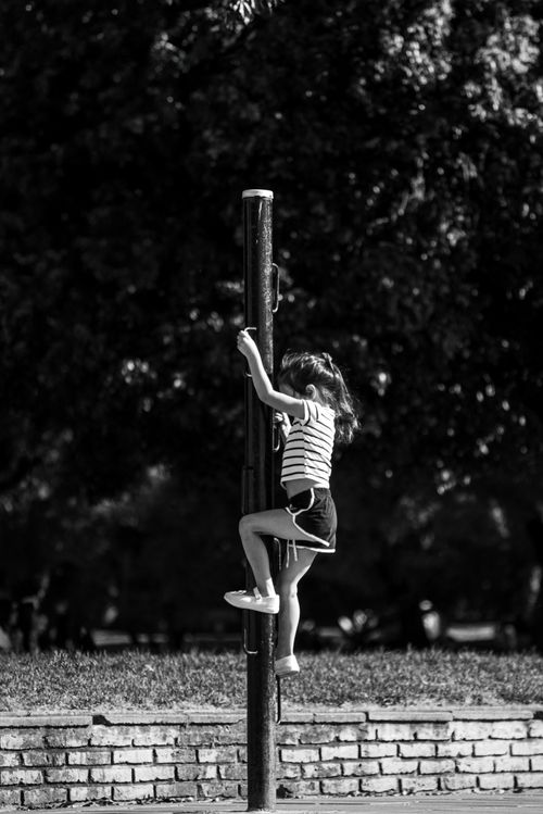 Free Black and white photo of a child climbing a pole in a park setting in Buenos Aires. Stock Photo