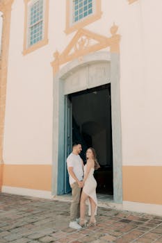 Couple in love standing near an elegant historic building entrance, romantic moment.