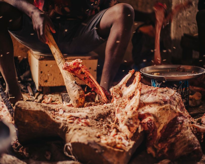 A man skillfully butchering meat using traditional tools in an indoor setting.