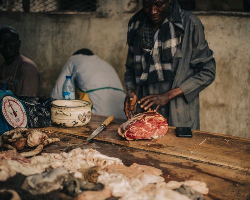 Free A skilled butcher preparing fresh meat at an indoor market stall with various cuts displayed. Stock Photo