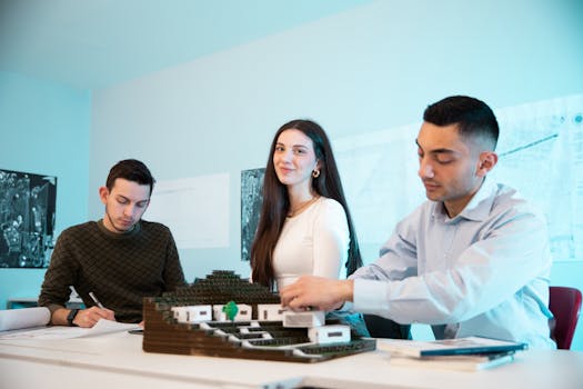 Three young architects working on a building model in a bright office setting.