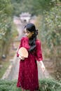 Woman in Red Dress Holding Fan in Garden