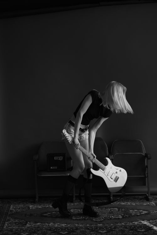 Free Energetic woman playing electric guitar indoors, hair in motion. Stock Photo