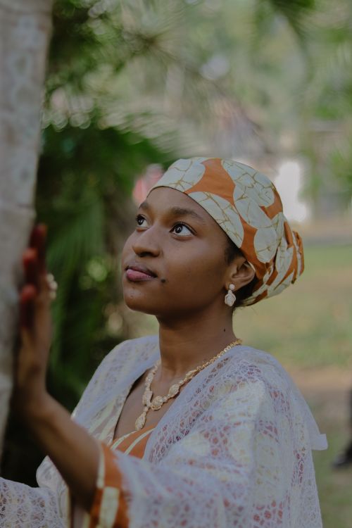 Free A woman in traditional clothing is looking upwards against a blurred green background. Stock Photo