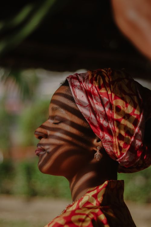 Free Close-up profile of a woman in vibrant clothing with artistic shadows on her face. Stock Photo