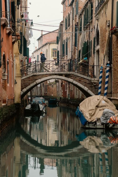 Free A picturesque Venetian canal showcasing a historic bridge on a misty day. Stock Photo