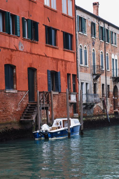 Free A cozy boat docked alongside vibrant historic buildings on a charming Venice canal. Stock Photo