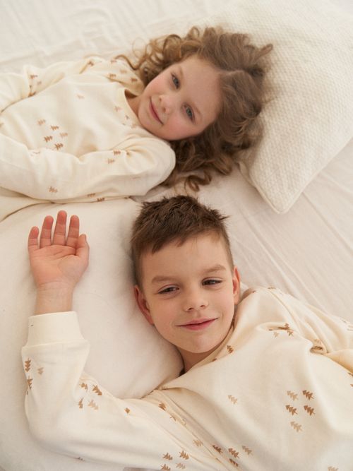 Free Two smiling children lying on bed in cozy pajamas, enjoying a moment of relaxation. Stock Photo