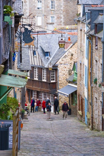 Fotomural Explora una pintoresca calle de adoquines en la ciudad medieval de Dinan, Francia, capturando un encanto atemporal y cultura vibrante.
