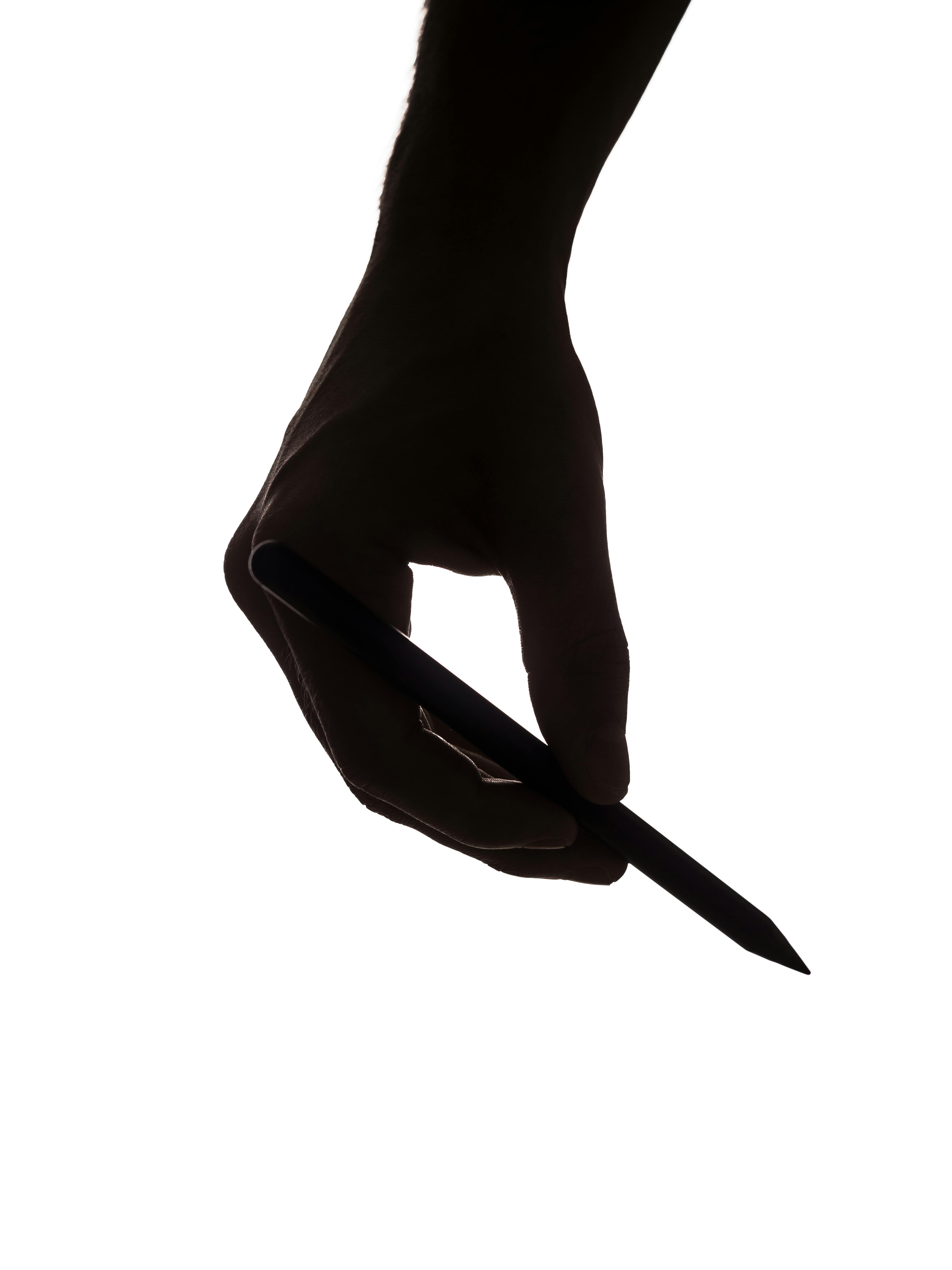 Gratis Silhouette artistica di una mano che impugna una matita su uno sfondo bianco, che sottolinea creatività e design. Foto a disposizione