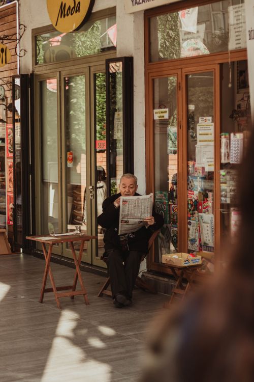 Free An elderly man enjoys reading a newspaper outside a shop in Istanbul, Turkey. Stock Photo