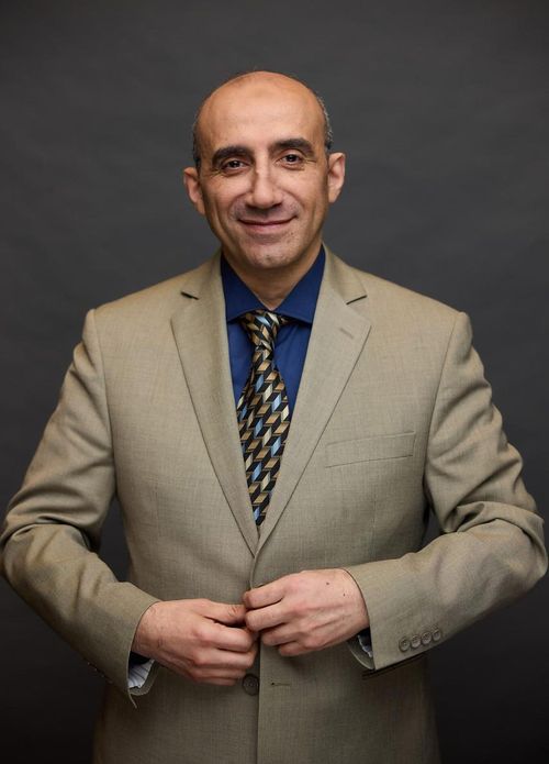 Free Confident man in a beige suit with a blue shirt and patterned tie. Stock Photo