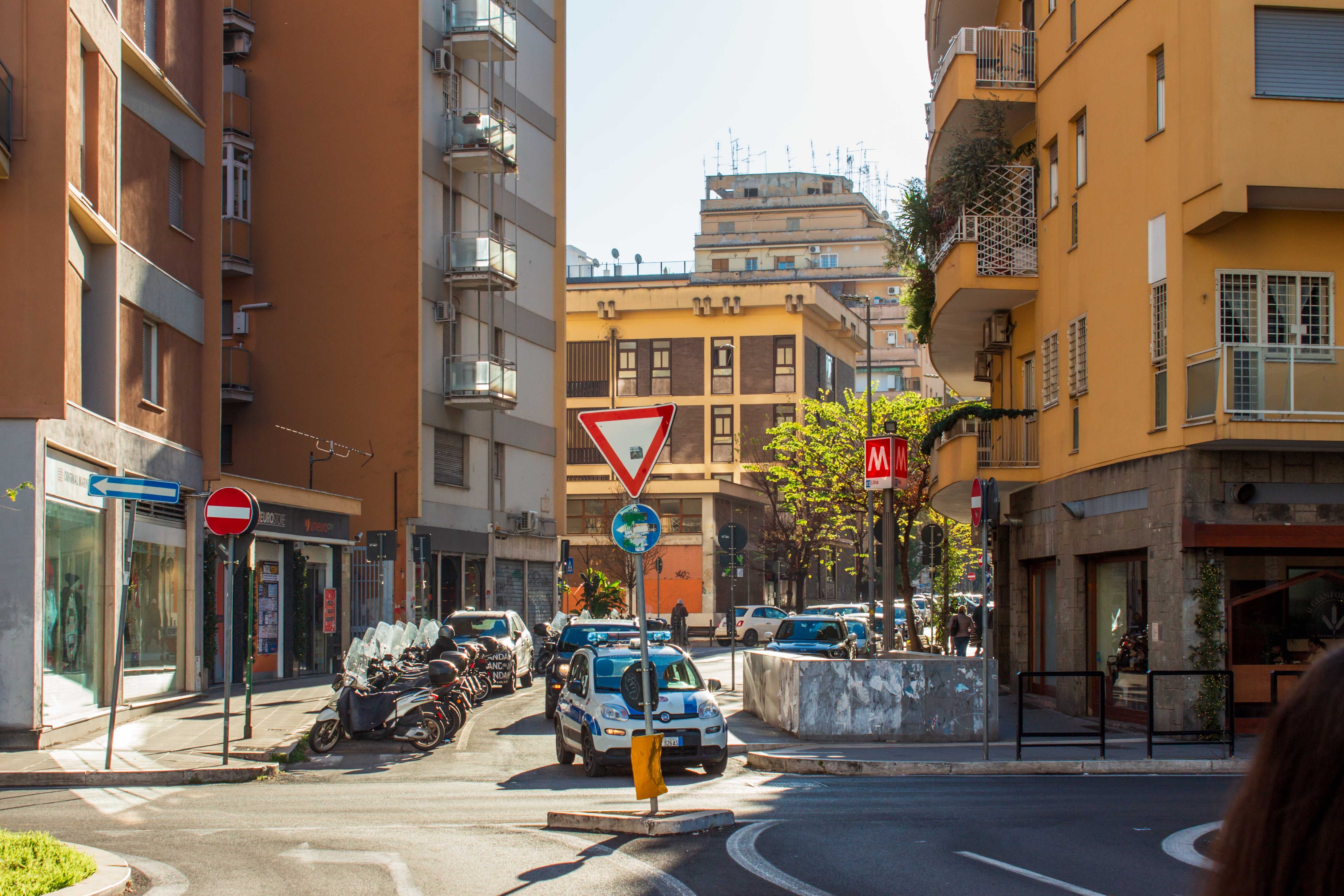 Vibrant street scene in Rome featuring traffic signs, police car, and urban buildings in the morning light.